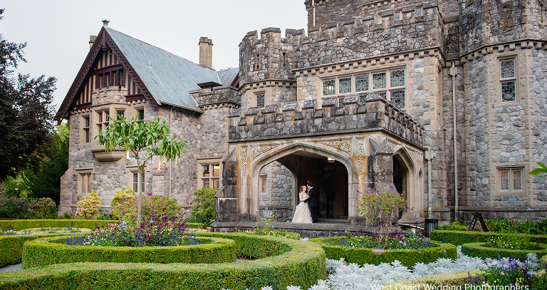 A newlywed couple posing for a picture in front of Hatley Castle