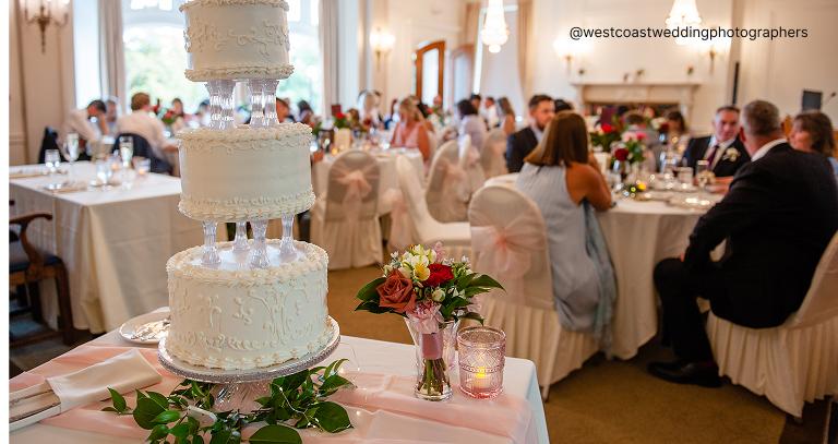 Elegant wedding reception at Hatley Castle with a tiered cake and guests seated at decorated tables